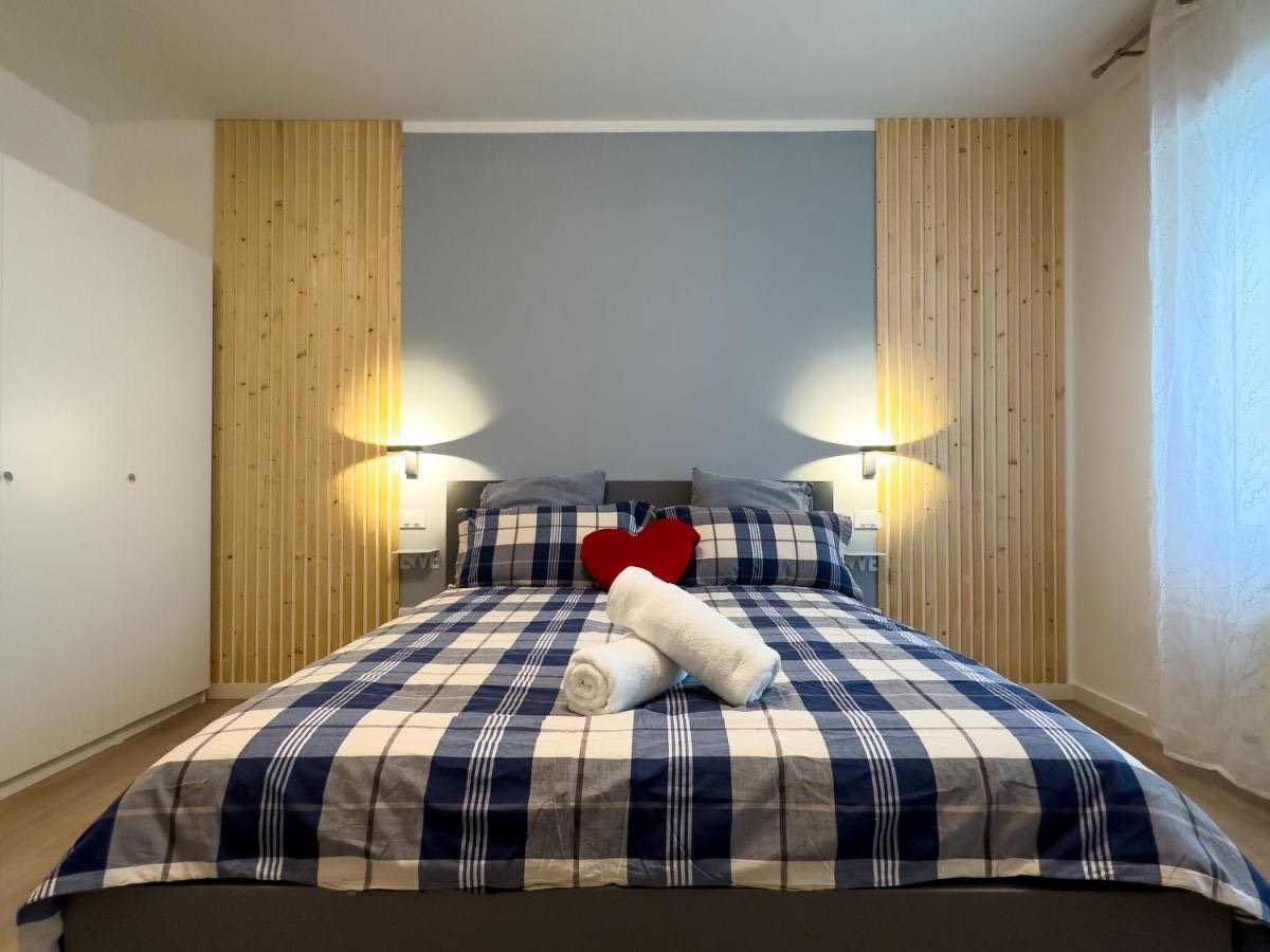 Camera matrimoniale con copriletto a quadri blu, parete azzurra e listelli in legno